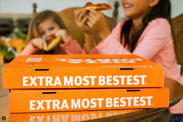 Children enjoying pizza with a bright orange box.