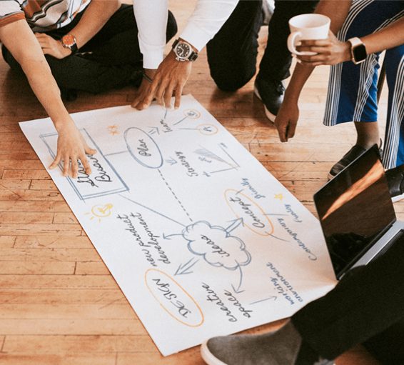 People collaborating over a large brainstorming diagram on paper.