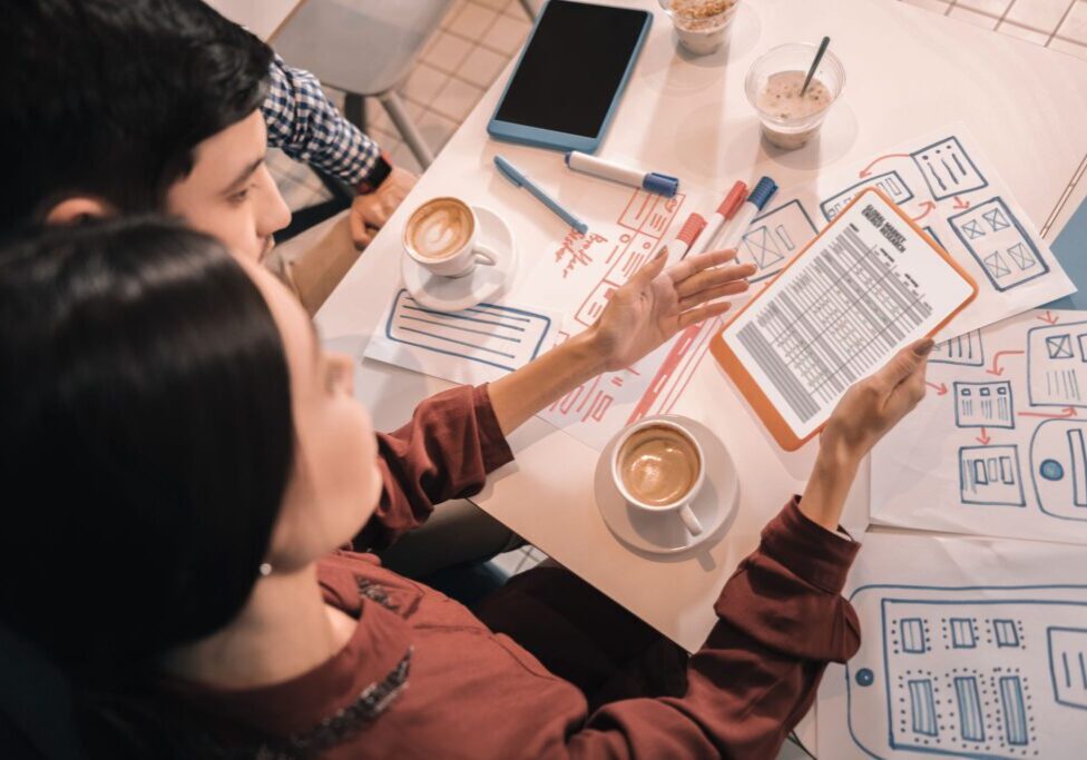 People reviewing documents over coffee at table.